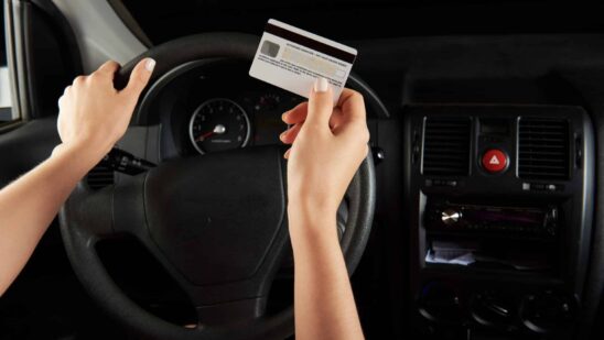 Driver hold credit card infront of car dashboard