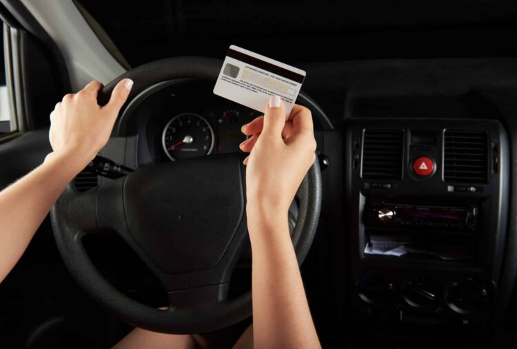 Driver hold credit card infront of car dashboard