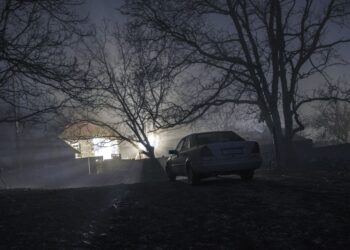 Silhouette of car and trees at night forest with fog, surreal lights mystical landscape