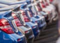 Selection of new metallic blue and gray cars lined up in dealership parking lot.