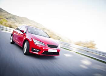 Red car driving fast on the road with motion blur