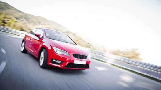 Red car driving fast on the road with motion blur