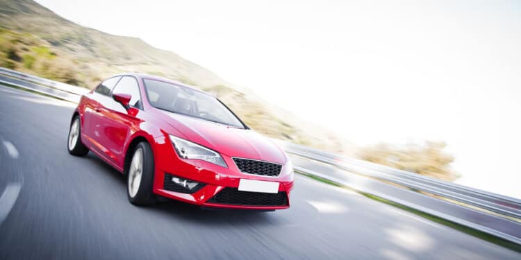 Red car driving fast on the road with motion blur