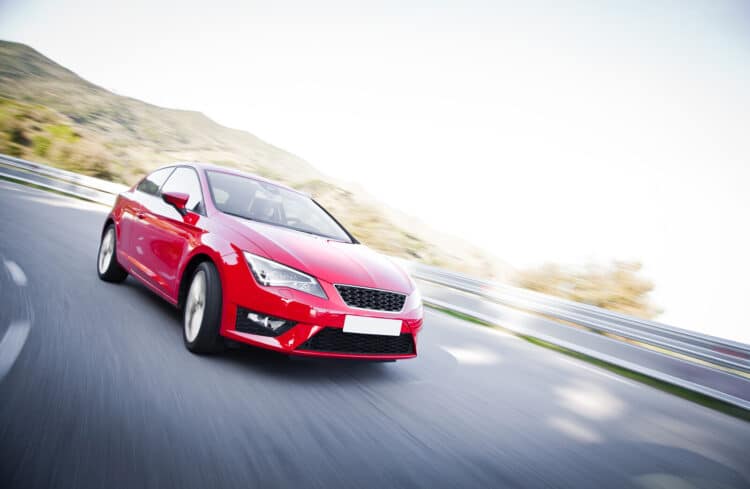 Red car driving fast on the road with motion blur