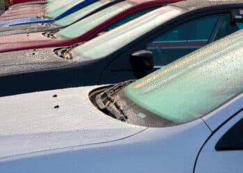 Cars on a dealer lot with dew on the windshield