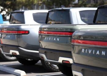 Rivian electric pickup trucks sit in a parking lot at a Rivian service center.