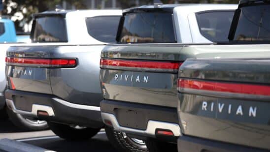 Rivian electric pickup trucks sit in a parking lot at a Rivian service center.