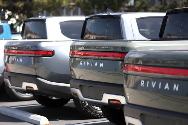 Rivian electric pickup trucks sit in a parking lot at a Rivian service center.