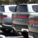 Rivian electric pickup trucks sit in a parking lot at a Rivian service center.