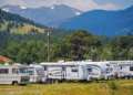 RVs lined up in a park in front of a mountain range