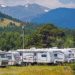 RVs lined up in a park in front of a mountain range