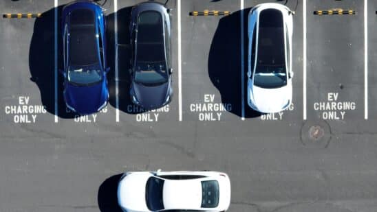 In an aerial view, Tesla cars recharge at a Tesla charger station