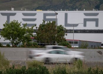 Vehicles pass the Tesla Inc. assembly plant in Fremont, California, U.S., on Monday, May 11, 2020. Elon Musk restarted production at Teslas only U.S. car plant, flouting county officials who ordered the company to stay closed and openly acknowledging he was risking arrest for himself and his employees.