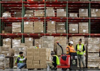 Workers apply labels to boxes. Photographer: Samuel Corum/Bloomberg
