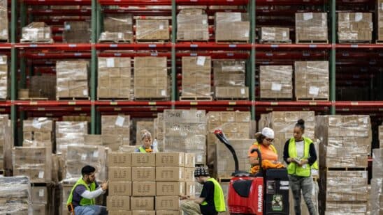 Workers apply labels to boxes. Photographer: Samuel Corum/Bloomberg