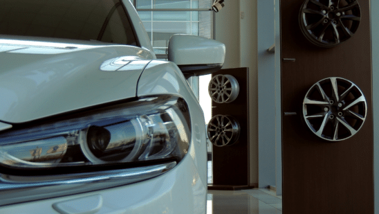 car in dealership showroom next to wheel rims