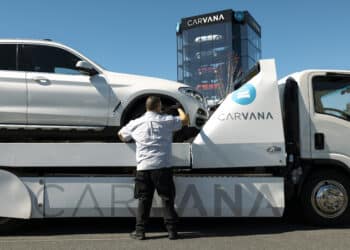 A worker unloads a vehicle from a flatbed truck at a Carvana vending machine location in Uniondale, New York, US, on Tuesday, April 16, 2024. Carvana Co. is scheduled to release earnings figures on May 1.