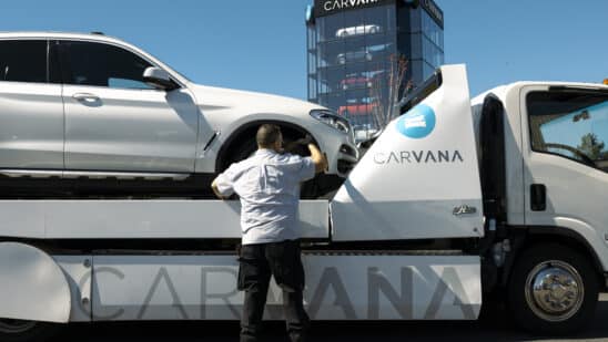 A worker unloads a vehicle from a flatbed truck at a Carvana vending machine location in Uniondale, New York, US, on Tuesday, April 16, 2024. Carvana Co. is scheduled to release earnings figures on May 1.