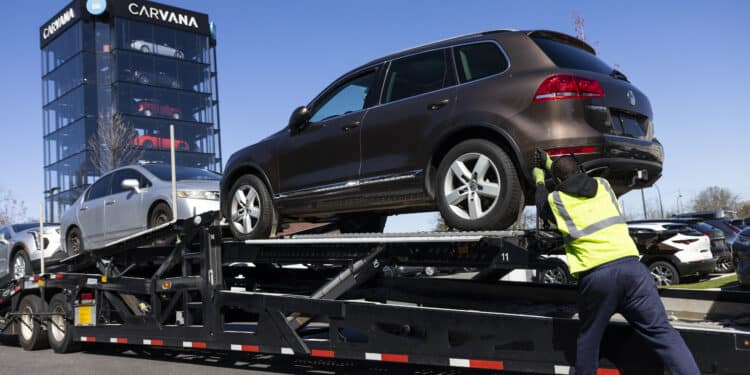 A worker loads vehicles onto a transporter at a Carvana vending machine location in Uniondale, New York, US, on Tuesday, April 16, 2024. Carvana Co. is scheduled to release earnings figures on May 1.