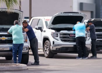 Customers look at vehicles for sale at a GMC Chevrolet dealership in Yuma, Arizona, US, on Monday, March 31, 2025. Whether Donald Trump's 25% tariffs on imported vehicles achieve the president's goal of revitalizing domestic auto manufacturing remains to be seen, but the levies that start April 3 are almost certain to push up the prices of new models if they stay in force for more than a few months. (Eric Thayer/Bloomberg)