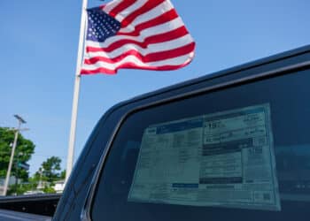 american flag by car as tariffs raise prices