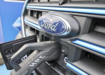 An electric Ford vehicle charging in front of Ford Motor Co. dealership.