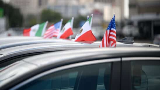 Mexican and American flags attached to vehicles at a Tricolor dealership in Houston.