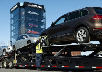 A worker loads vehicles onto a transporter at a Carvana site in New York. Photographer: Angus Mordant/Bloomberg