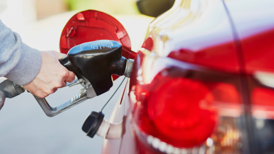 close up of red car and person pumping gas