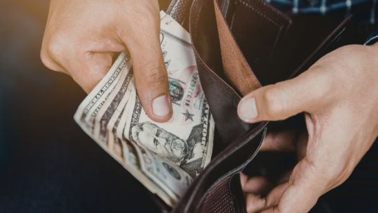 A person removes U.S. currency from a wallet.