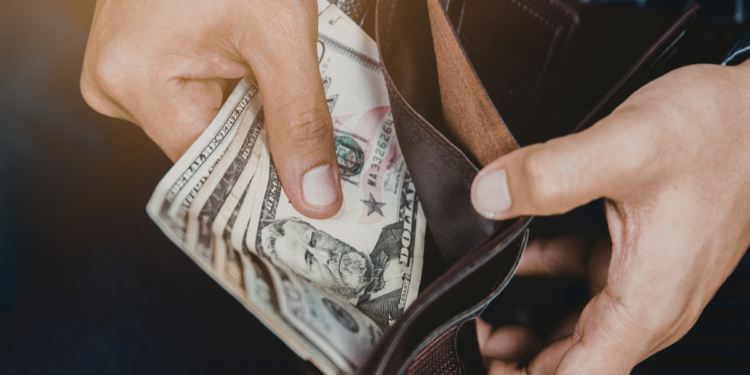 A person removes U.S. currency from a wallet.