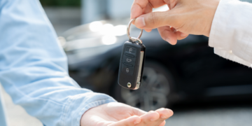 A person hands a car key fob to another person.