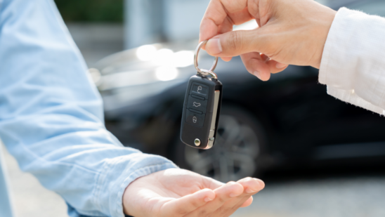 A person hands a car key fob to another person.