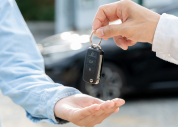 A person hands a car key fob to another person.