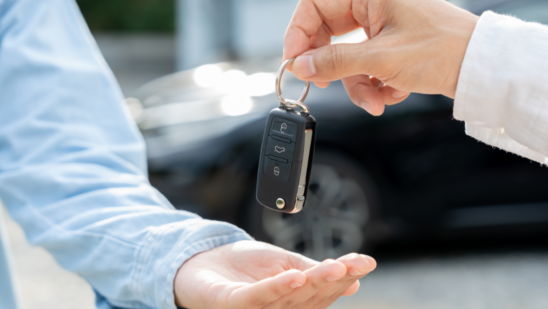 A person hands a car key fob to another person.