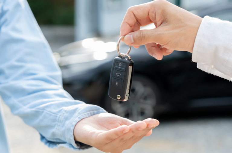 A person hands a car key fob to another person.
